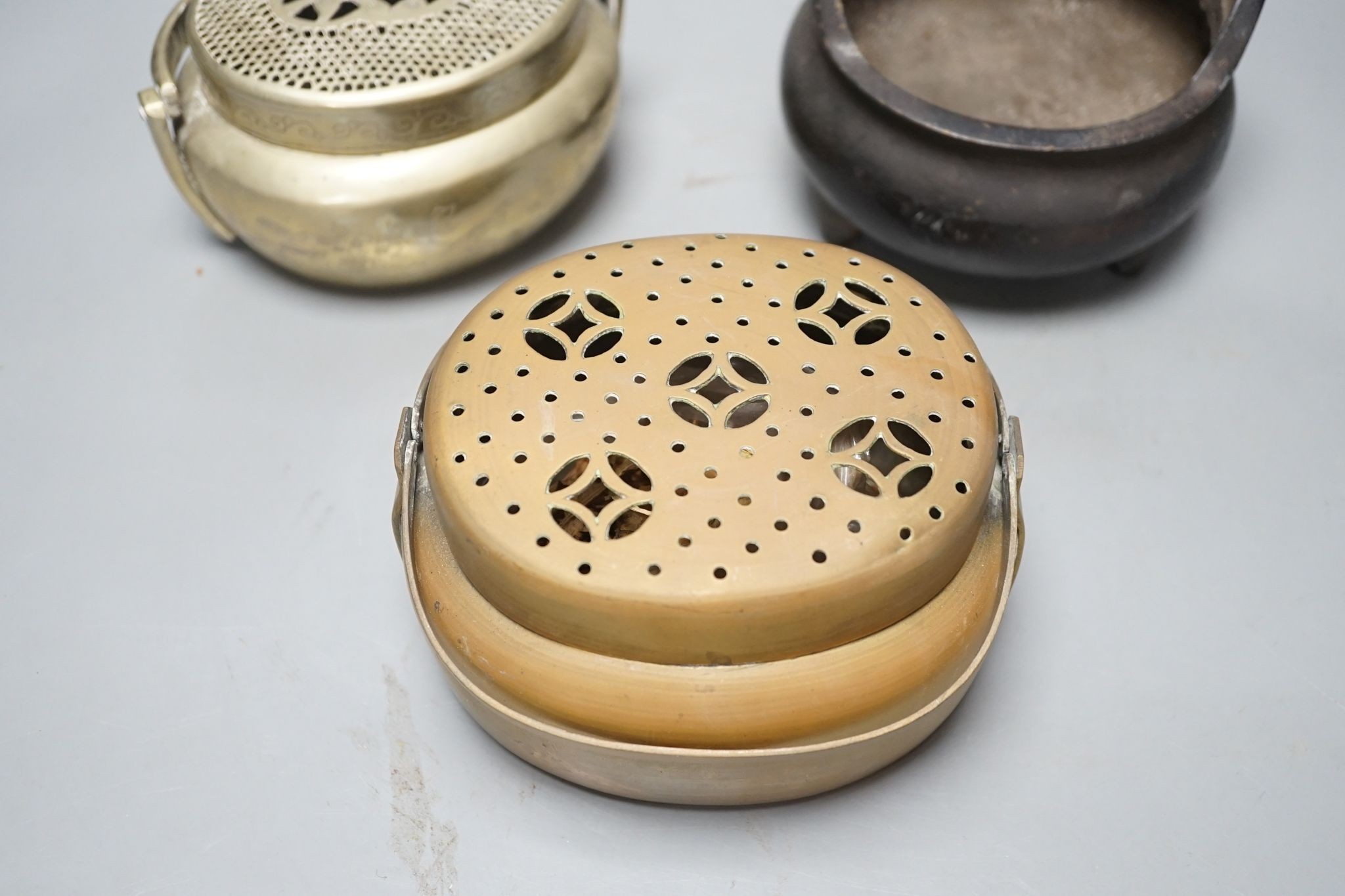 A Chinese bronze tripod censer, 13.5cm and two brass or bronze hand warmers